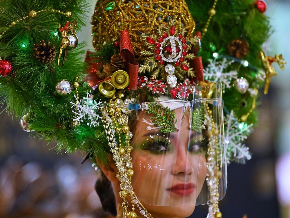 A model dressed as a Christmas tree and wearing a face shield poses for photos in a shopping mall in Bangkok on Dec. 24, 2020.