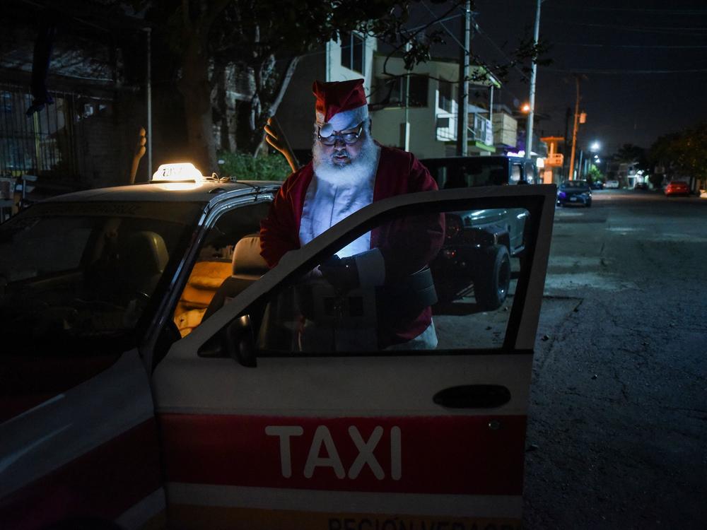 Francisco Monzon, 50, a taxi driver dressed as Santa Claus, looks at his phone, in Boca del Rio, Veracruz state, Mexico, on Dec. 24, 2020.