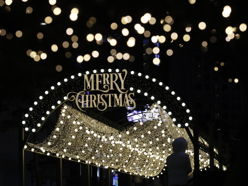 A woman wearing a face mask as a precaution against the coronavirus takes a photo near a Christmas decoration in Seoul, South Korea, Dec. 24, 2020.