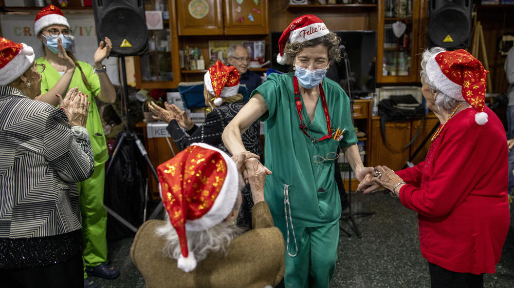 A seniors' residence employee (second right) dances with residents as a band plays on Christmas Eve at Las Praderas home on Dec. 24, 2020, in Pozuelo de Alarcon, near Madrid, Spain. The residence is free of COVID-19 cases.