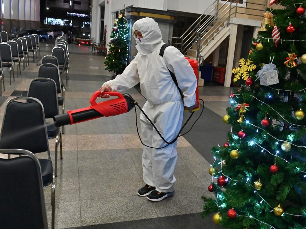 A worker wearing personal protective equipment disinfects the Holy Redeemer Church in Bangkok after a Christmas Eve mass. Thailand is one of many countries now seeing a surge in cases.