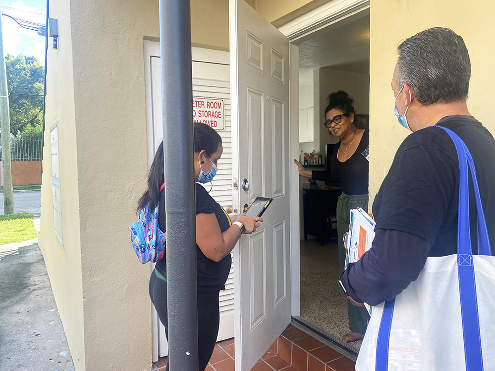 In their canvassing of a predominantly Cuban American neighborhood in October, Díaz (right) and another community outreach worker, María Elena González (left), spoke with Gloria Carvajal about how to get a COVID-19 test.