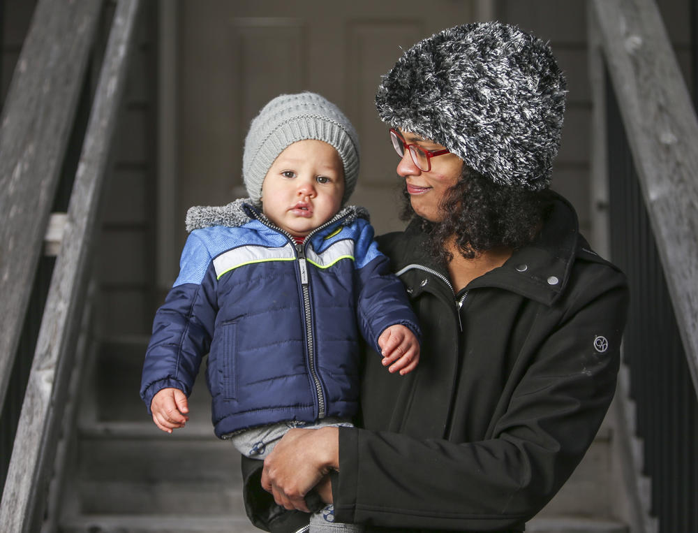 Erika Pohlman holds her son Orion Davis, 14 months, on the front stairs of their home in Solon, Iowa.