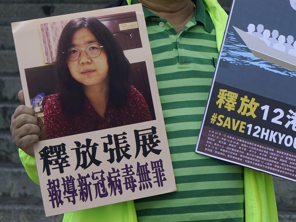 A pro-democracy activist holds placards with the picture of Chinese citizen journalist Zhang Zhan outside the Chinese central government's liaison office, in Hong Kong, Monday. Activists demand the release of Zhang, as well as the 12 Hong Kong activists detained at sea by Chinese authorities.