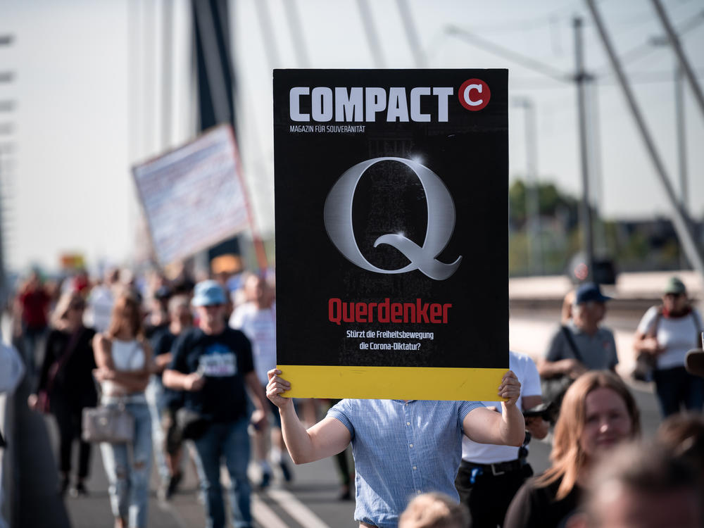 A demonstrator holds a sign saying Querdenker (