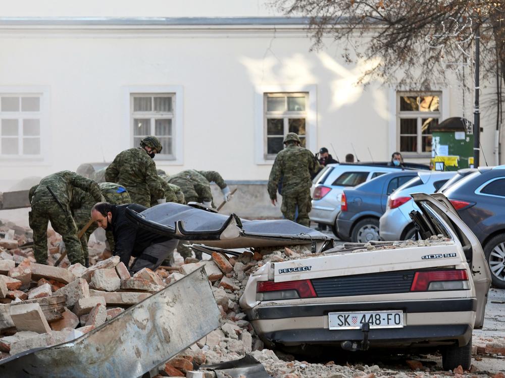 Croatian soldiers clean rubble next to damaged buildings Tuesday in Petrinja, a town of about 24,000 residents.