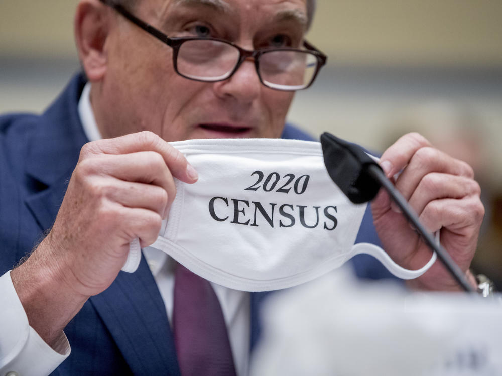 Census Bureau Director Steven Dillingham holds up his mask with the words 