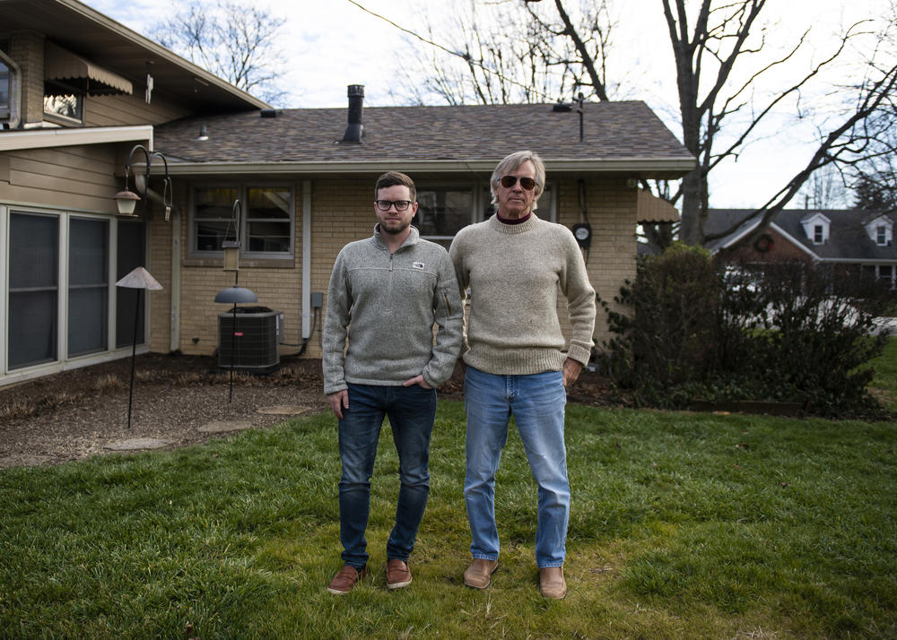 Scott Williams (right) and his son, Andy Williams, stand outside Scott Williams' home in Lebanon, Ind. Scott Williams lost his wife Debbie in April to hypothyroidism. The family has yet to have a proper funeral due to the pandemic.