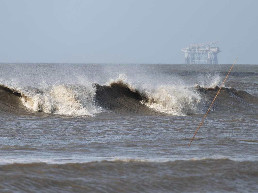 Hurricane Laura sends large waves crashing on a beach in Cameron, La., on Aug. 26 as an offshore oil rig appears in the distance. The most active hurricane season on record was just one of many challenges facing the oil industry this year — aside from the attention-grabbing crisis of the pandemic.