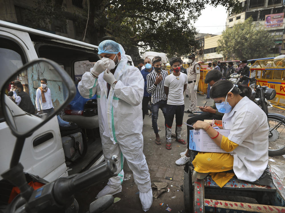 A health worker gets ready to take samples from people to test for COVID-19 as another registers them at a marketplace last month in New Delhi.