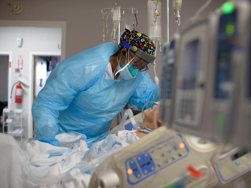 Health care worker Demetra Ransom comforts a patient in the COVID-19 ward at United Memorial Medical Center in Houston, Texas. on Dec. 4. The U.S. has surpassed 20 million confirmed coronavirus cases.