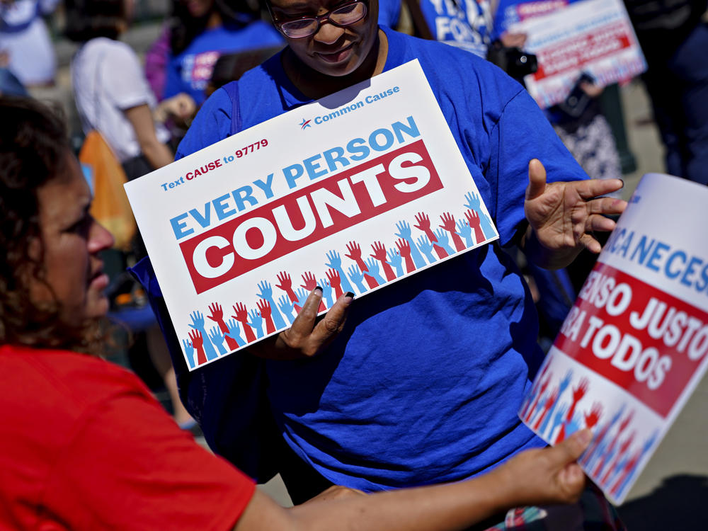 A demonstrator hands out a sign about the 2020 census outside the U.S. Supreme Court in Washington, D.C., in 2019. The Census Bureau is projecting the first set of census numbers won't be ready until February, Trump administration attorneys told a federal judge on Monday.