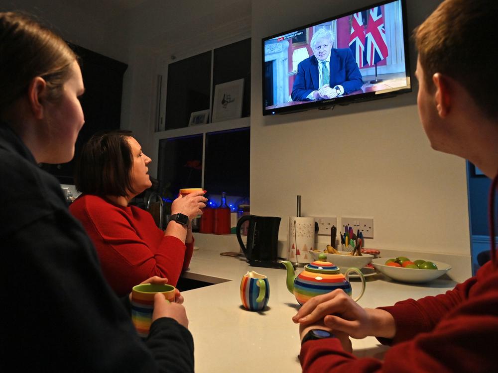 A family gathers around the television Monday in Liverpool, England, to watch Prime Minister Boris Johnson speak to the nation about the new lockdown.