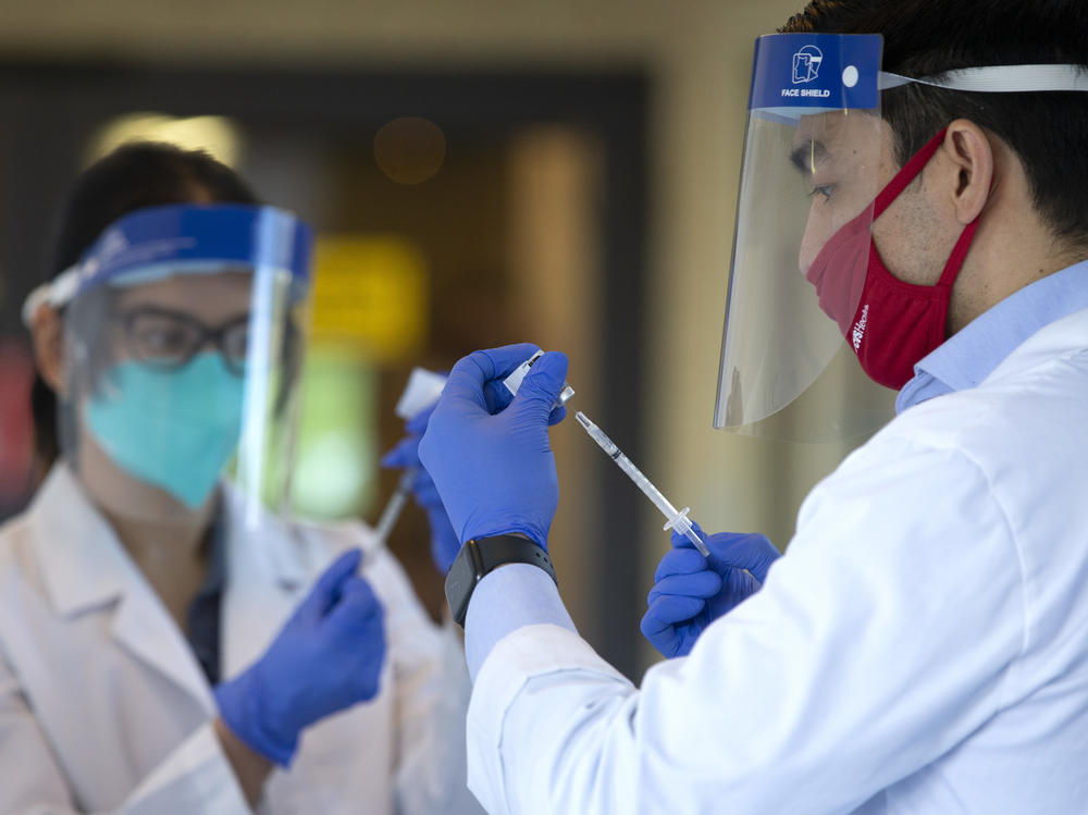 Pharmacists prepare doses of a COVID-19 vaccine last week at the Life Care Center of Kirkland in Kirkland, Wash. The nursing home was an early epicenter for coronavirus outbreaks in the United States.