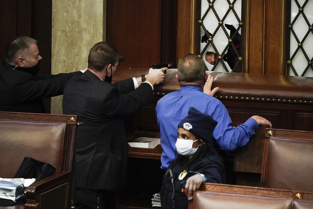 Police with guns drawn face off with protesters trying to break into the House chamber Wednesday at the Capitol.