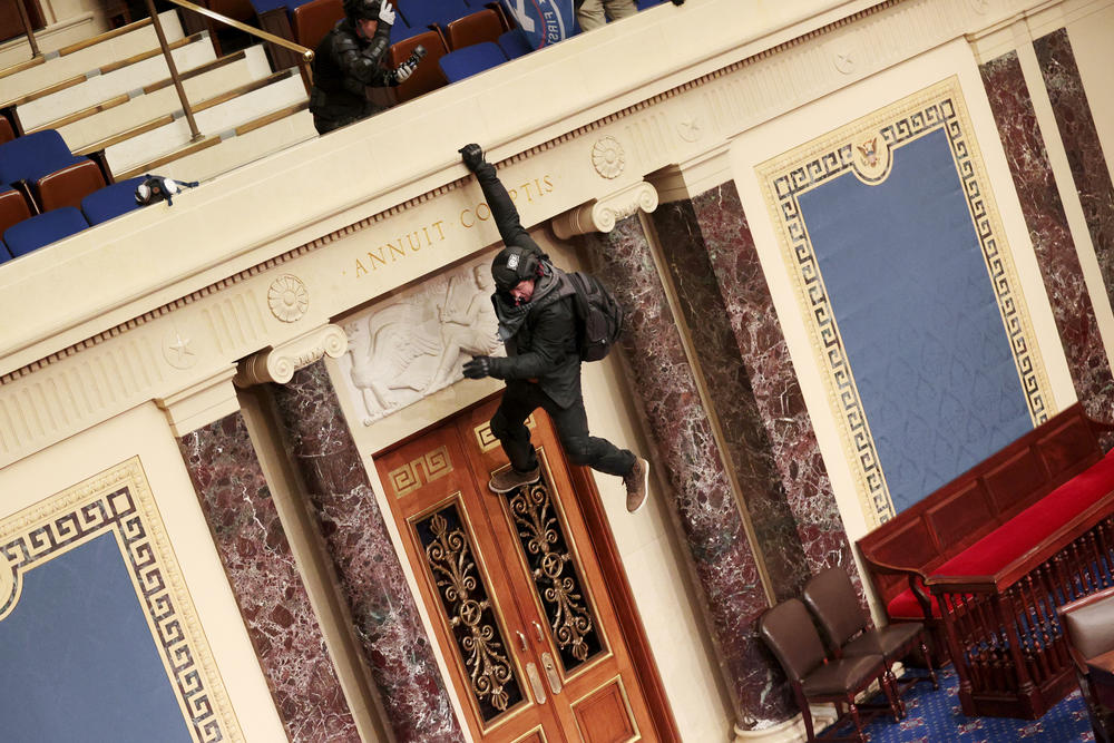 An extremist hangs from the balcony in the Senate chamber.