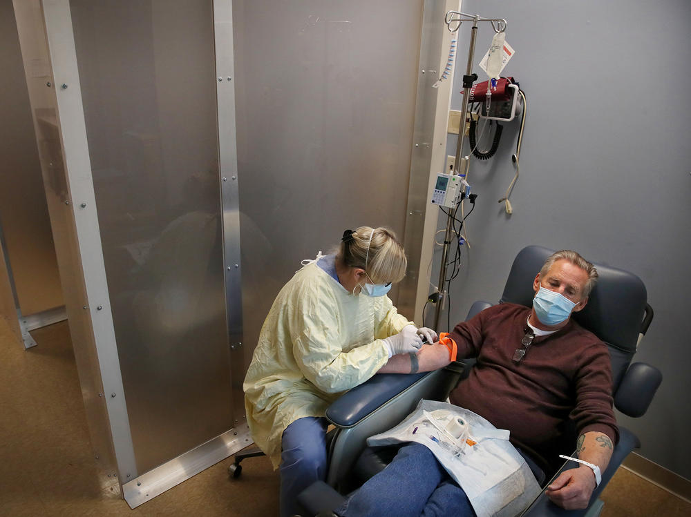 Nurse Janet Gilleran prepares to treat COVID-19 patient Mike Mokler with bamlanivimab, a monoclonal antibody drug from Eli Lilly, at the Respiratory Infection Clinic of Tufts Medical Center in Boston on Dec. 31, 2020.