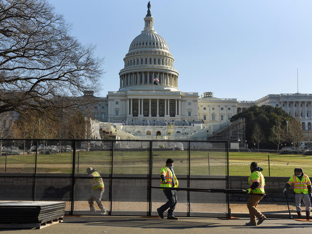 Workers install a fence in front of the U.S. Capitol on Thursday, one day after rioters stormed the building.