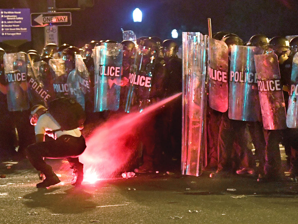 An anti-racism protester near Lafayette Square in Washington, D.C., in May is tear-gassed as he attempts to retrieve a flare thrown at police.