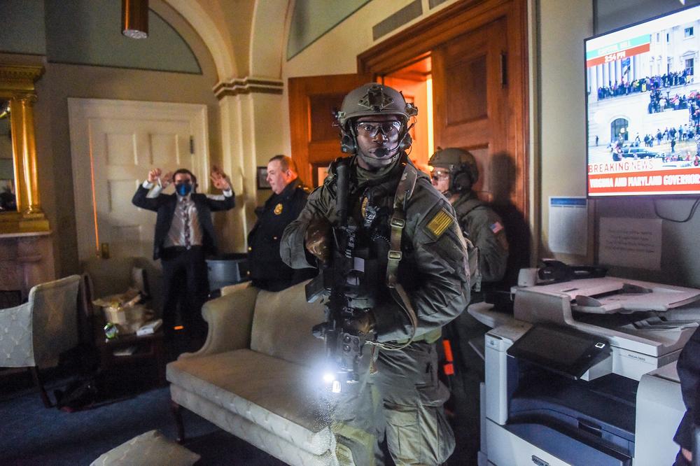 A Congress staffer holds his hands up while Capitol Police Swat team check everyone in the room as they secure the floor of Trump supporters who mobbed the Capitol building.