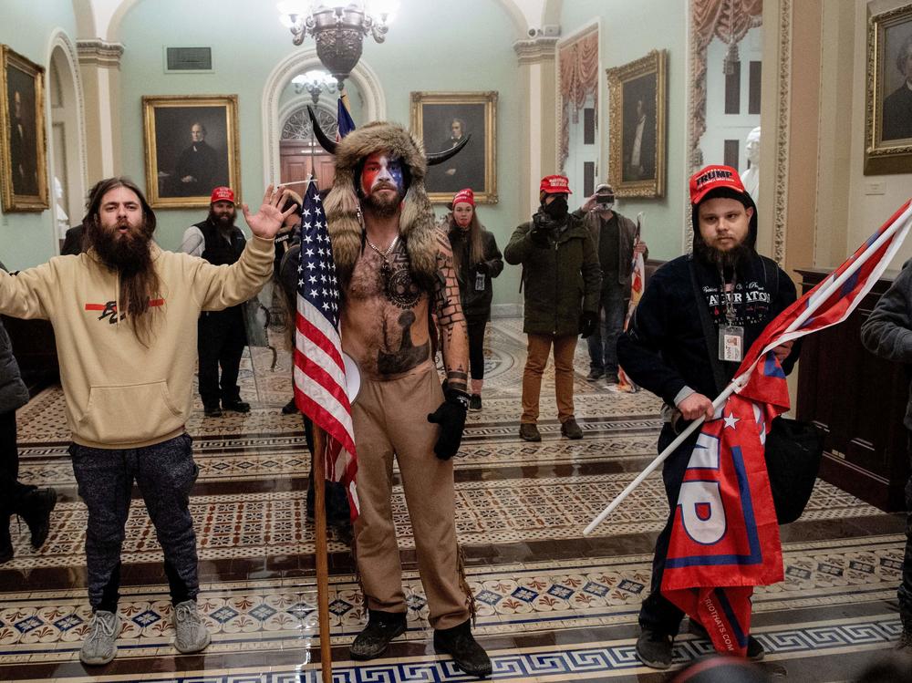 Supporters of President Trump, including Jake Angeli (center), a QAnon supporter known for his painted face and horned hat, stand inside the U.S. Capitol on Jan. 6. Demonstrators breached security and entered the Capitol as Congress was in the process of tallying the 2020 electoral vote count.