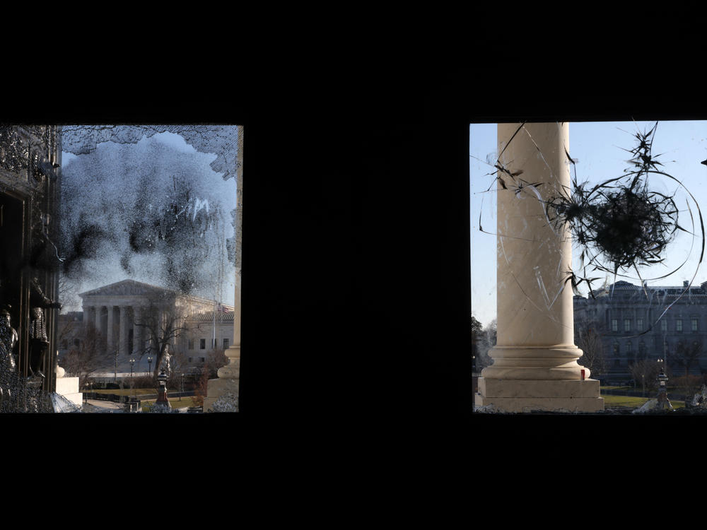 The U.S. Supreme Court is seen through a broken window at an entrance of the U.S. Capitol Wednesday.