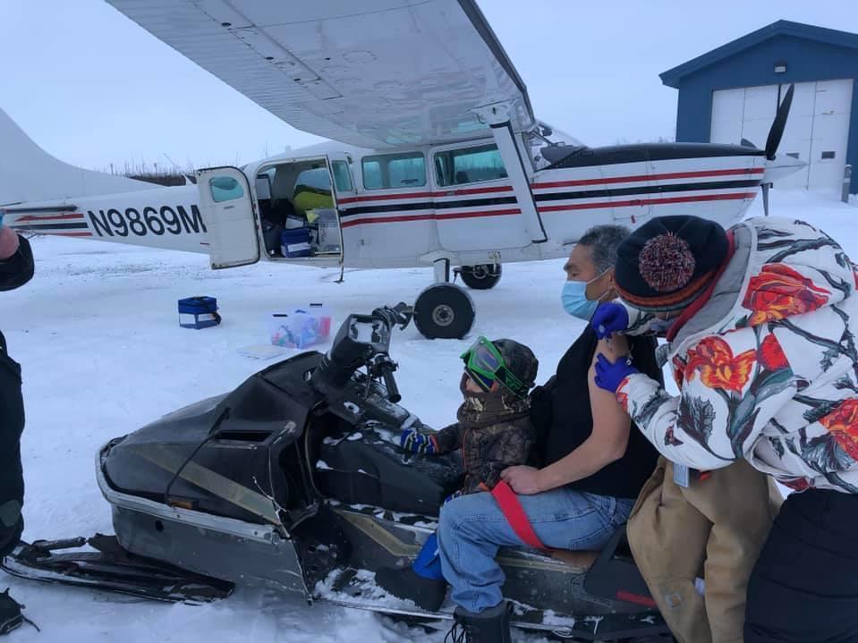 Sarah Lind, a nurse with Yukon-Kuskokwim Health Corp., Southwest Alaska's tribal health care provider, vaccinates James Evan in December. They're standing on the tarmac in the village of Napakiak, where Evan works for YKHC at the clinic.