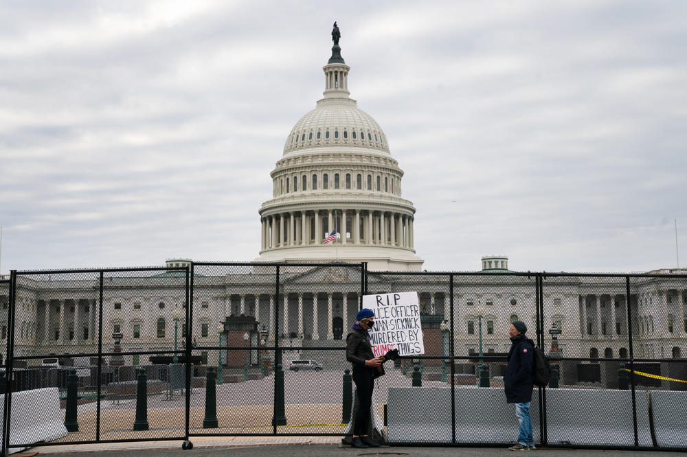 A person outside the U.S. Capitol holds a sign for U.S. Capitol Police officer Brian Sicknick who died from injuries he sustained during the siege on the Capitol by pro-Trump extremists.