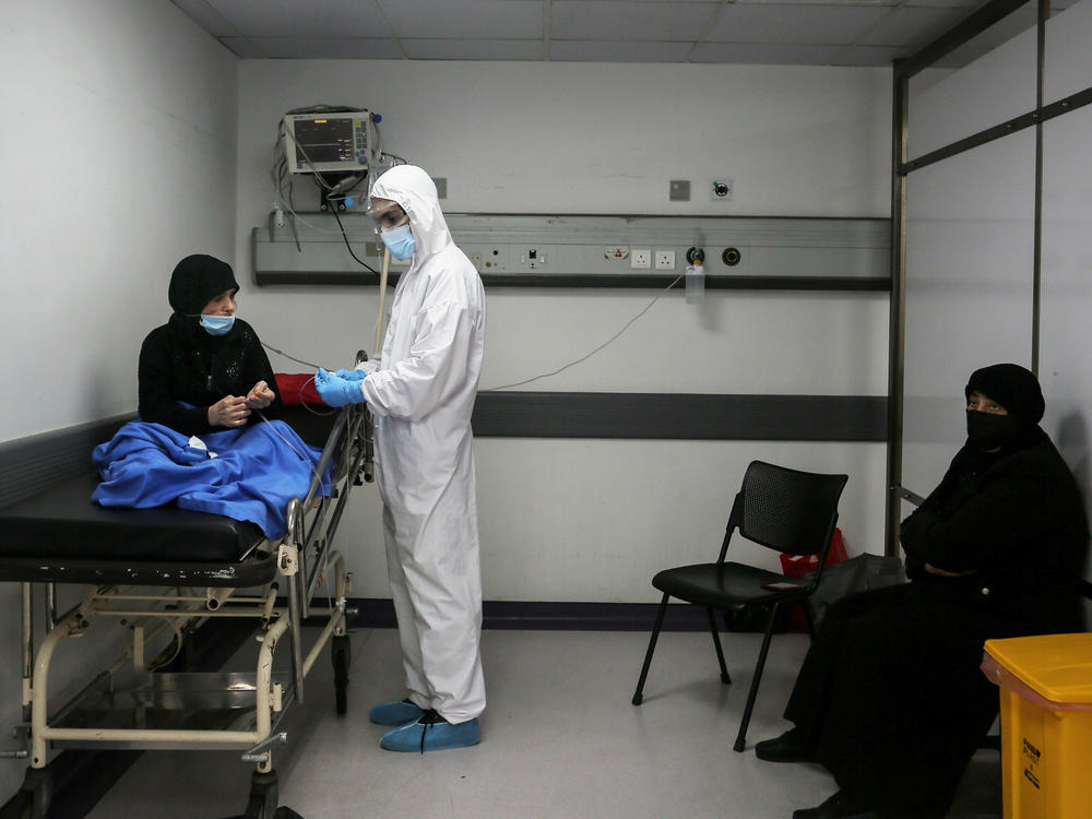 Inside an emergency room at Rafik Hariri Hospital on Nov. 17, a medic wearing full protective gear checks a woman who might have the coronavirus. Beirut hospitals are reaching maximum capacity amid an influx of coronavirus patients.