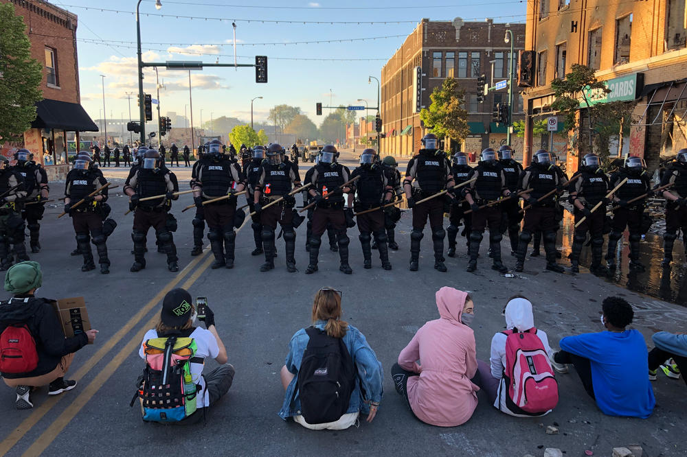 People sit on the street in front of a row of police officers during a rally in Minneapolis last year.