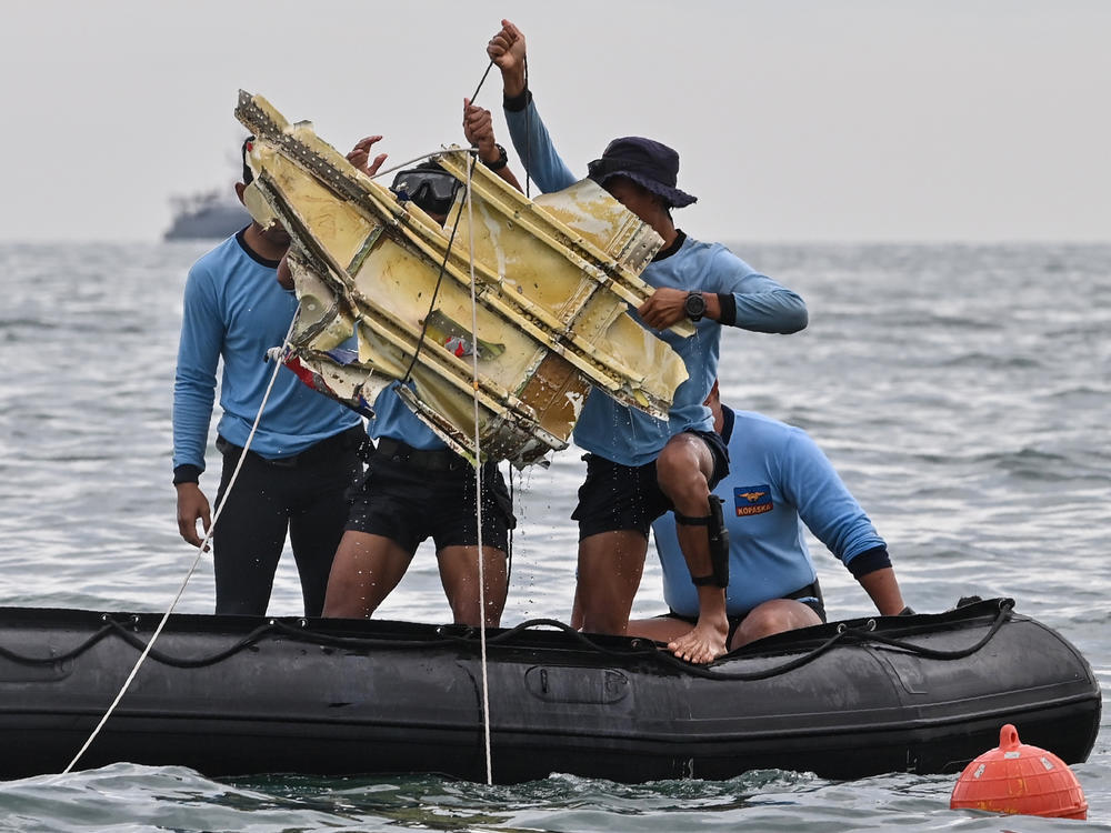 Indonesian Navy divers hold wreckage from Sriwijaya Air flight 182 during a search and rescue operation at sea near Lancang island on Sunday.