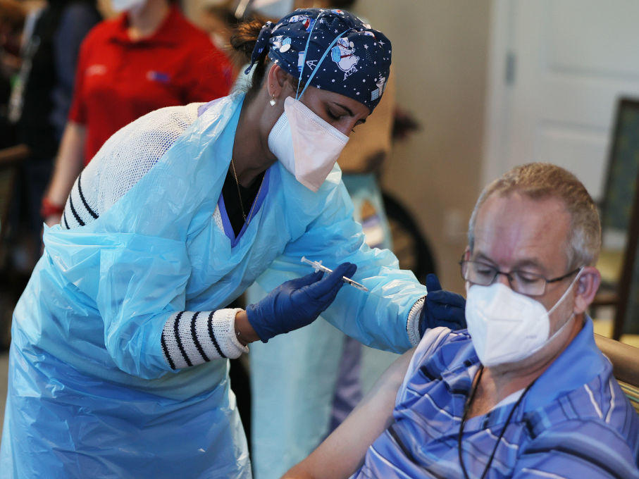 A health care worker with the Florida Department of Health administers a Pfizer-BioNtech COVID-19 vaccine at a retirement community in Pompano Beach, Fla. New Trump administration guidance arrived Tuesday, urging states to make all people over 65 eligible for the vaccine.