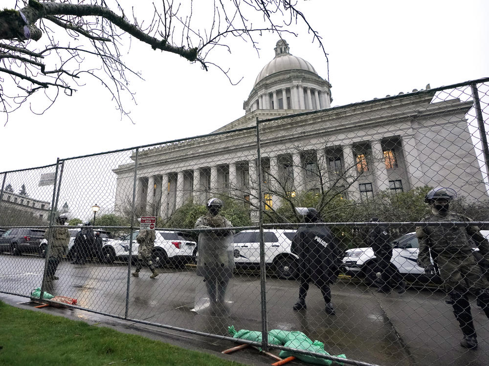 Members of the Washington National Guard stand near a fence surrounding the Capitol in Olympia, Wash., in anticipation of protests on Jan. 11, 2021.