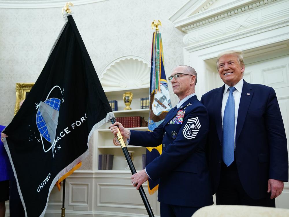 President Trump presedisplays the U.S. Space Force flag in the Oval Office last May. The new command plans to move its headquarters from a temporary location in Colorado to Alabama in 2023.