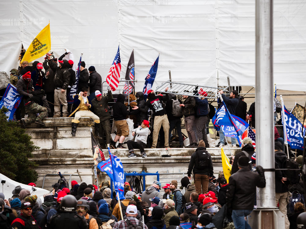 Pro-Trump extremists climb the walls of the U.S. Capitol on Jan. 6. The pro-Trump mob broke windows of the Capitol and clashed with police officers. Now there's debate about whether federal charges of seditious conspiracy should be used against some of the rioters.