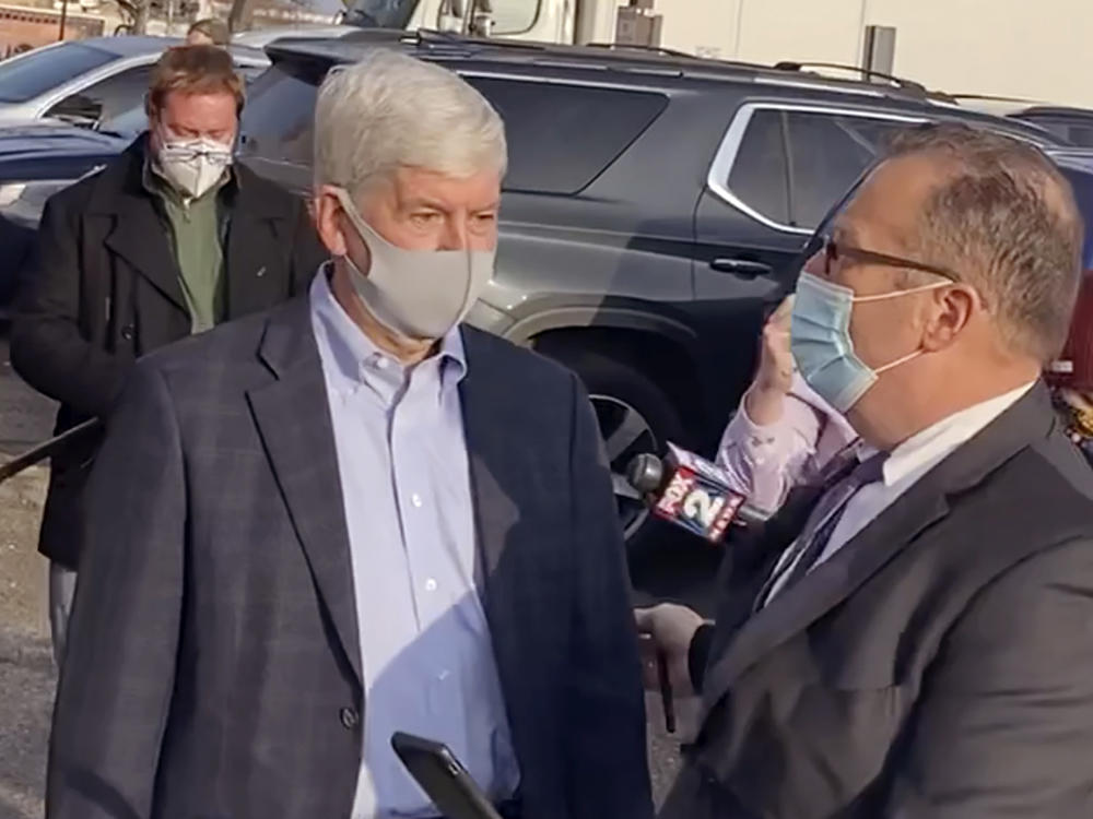 In this image taken from video, former Michigan Gov. Rick Snyder, left, with his lawyer, Brian Lennon, leave Genesee County Court in Flint, Mich., after a initial court appearance via Zoom on two misdemeanor counts of willful neglect of duty in connection to the Flint water crisis.