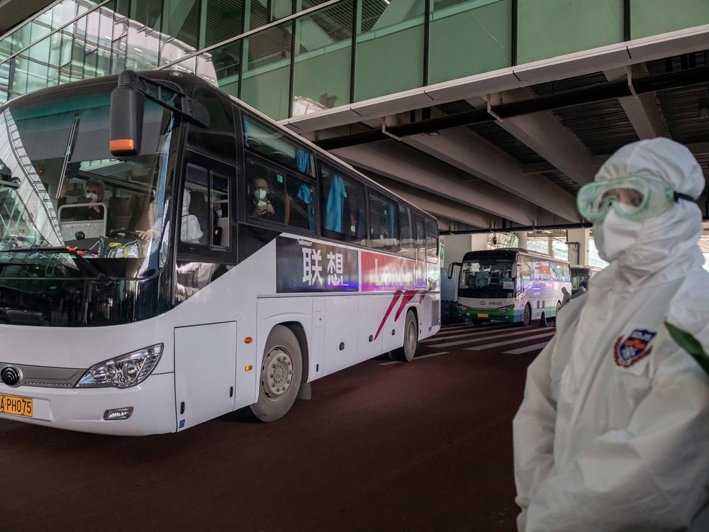 A bus carrying members of the World Health Organization team investigating the origins of the COVID-19 pandemic leaves Wuhan's airport following their arrival at a cordoned-off section in the international arrivals area on Thursday.
