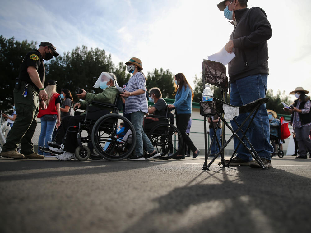People lined up to receive the COVID-19 vaccine at a mass vaccination site in Disneyland's parking lot in Anaheim, Calif. on Jan. 13. The state says all residents 65 or older are now eligible to receive the vaccine.