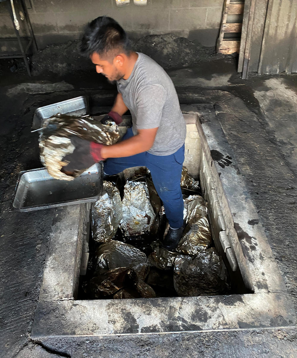 A kitchen employee hauls another beef head from the pit. Vera's is believed to be the last restaurant in Texas that cooks <em>barbacoa de pozo </em>the traditional way — underground.