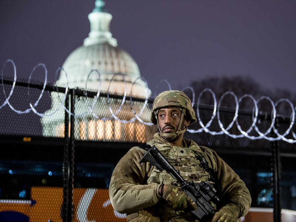 A member of the Virginia National Guard stands outside the razor wire fencing surrounding the U.S. Capitol on Friday. Up to 25,000 troops are expected by Inauguration Day.