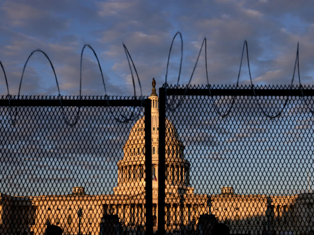 The U.S. Capitol is seen behind a fence with razor wire during sunrise Saturday. The FBI has warned of additional threats in the nation's capital and in all 50 states.