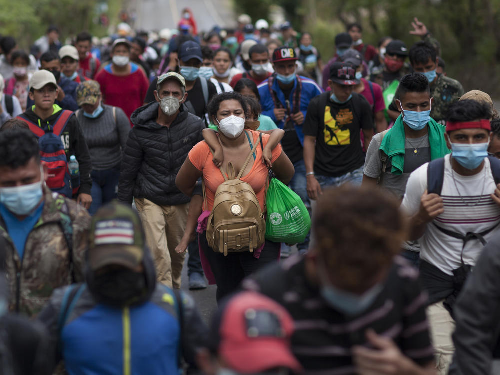 A Honduran migrant woman carries a child on her back as they travel with other migrants by foot along a highway in Chiquimula, Guatemala, on Saturday, in hopes of reaching the U.S. border.