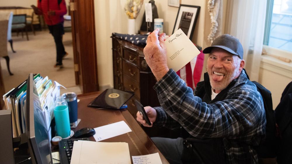 Richard Barnett, a supporter of President Trump, holds a piece of mail as he sits inside the office of Speaker of the House Nancy Pelosi after pro-Trump rioters breached the U.S. Capitol in Washington, D.C., on Jan. 6.
