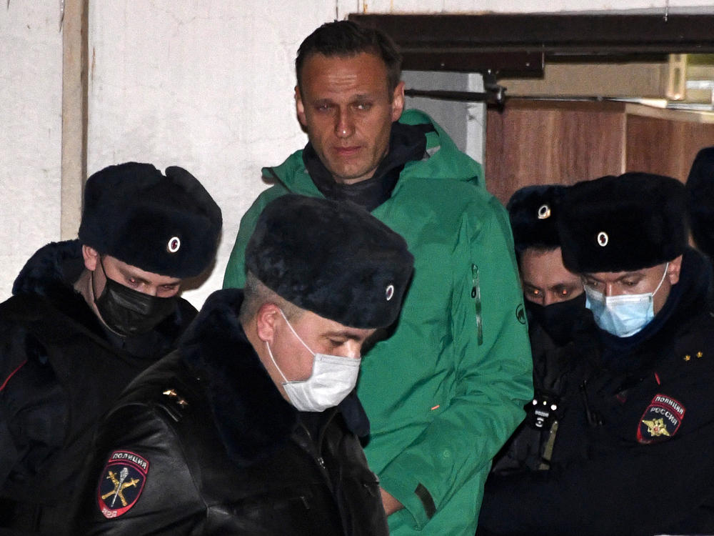 Opposition leader Alexei Navalny is escorted out of a police station in Khimki, outside Moscow, following the court ruling that ordered him jailed for 30 days.
