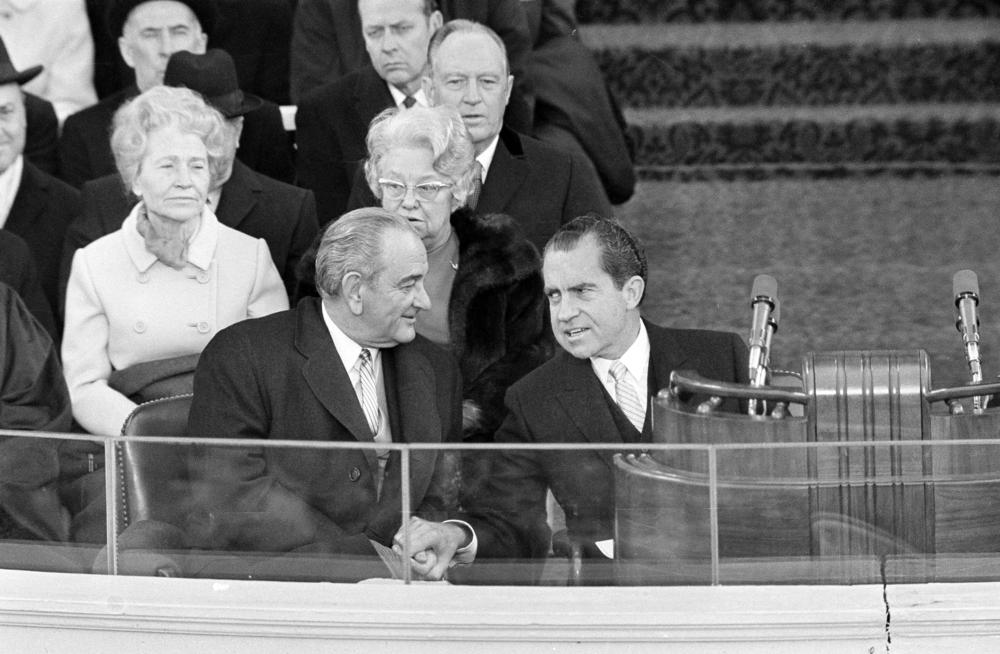 President Richard Nixon and former President Lyndon B. Johnson clasp hands as they sit on the inaugural stand where Nixon took the oath of office on Jan. 20, 1969.