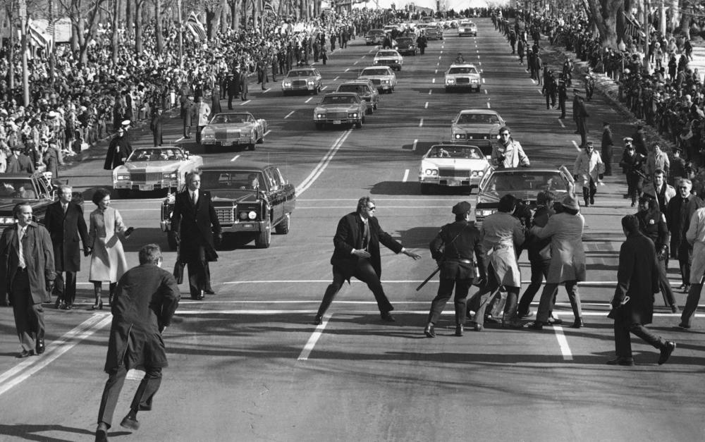 President Jimmy Carter and first lady Rosalynn watch (left) as police and Secret Service officials remove a spectator (right) who burst into the Inaugural Parade on Pennsylvania Avenue on Jan. 20, 1977.