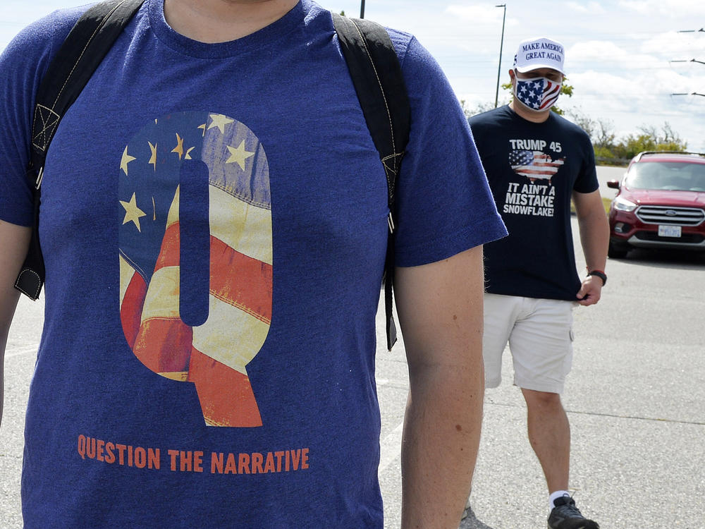 A man wears a QAnon shirt while boarding a shuttle bus in Londonderry, N.H., on Aug. 28, 2020.