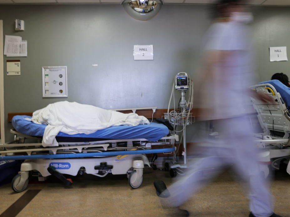 A patient lies on a stretcher in the hallway of the overloaded emergency room at Providence St. Mary Medical Center amid a surge in COVID-19 patients in Southern California in late December. Average new daily infections are now going down in California and much of the country.