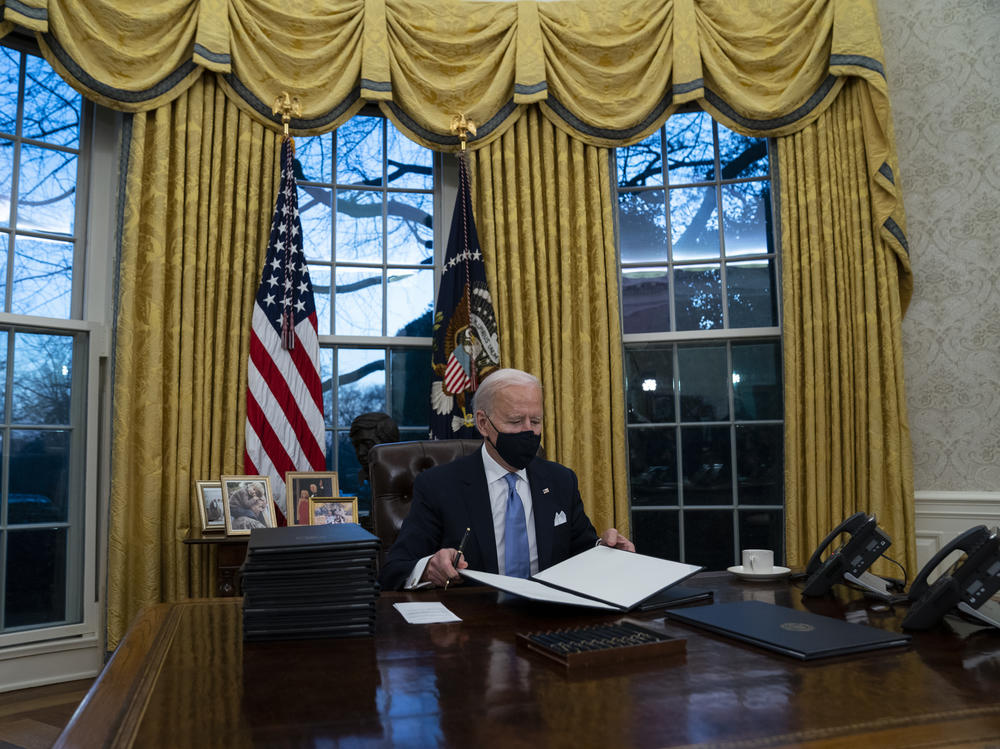 President Biden signs executive actions hours after his inauguration on Wednesday. He is expected to reverse several Trump-era policies.