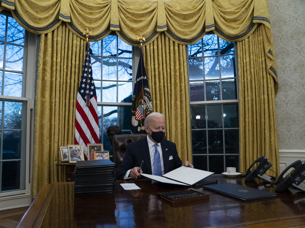 President Biden signs executive actions hours after his inauguration on Wednesday. He is expected to reverse several Trump-era policies.